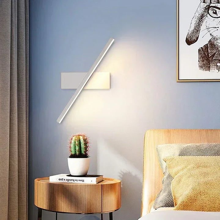 Modern bedroom with wooden side table, cactus plant, and LED wall-mounted lamp.