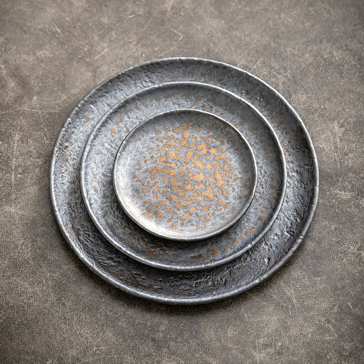 Top-down view of nested shallow ceramic plates, rustic grey stoneware serving set, 22/17/12 cm