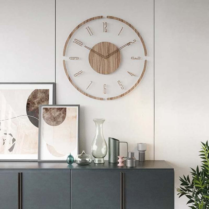 Wooden wall clock on a white wall above a gray cabinet with decorative items.