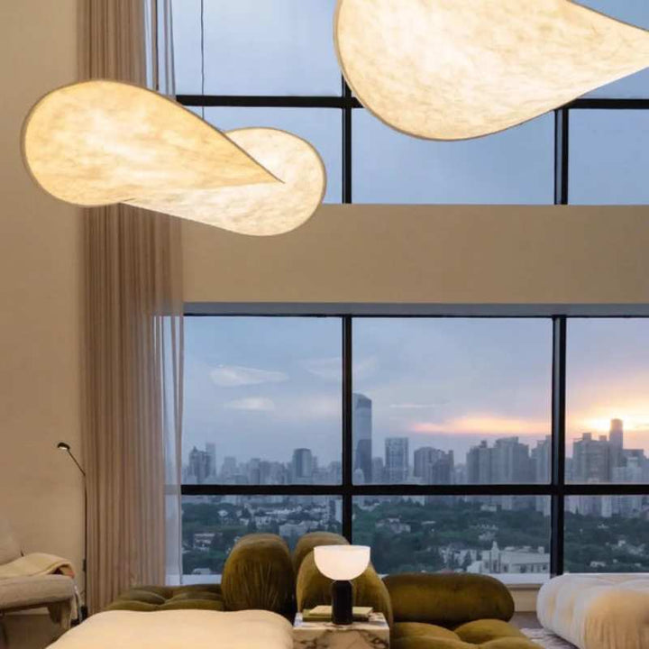 Elegant silk pendant lights with organic wabi sabi shapes hanging in a high-ceiling modern living room.