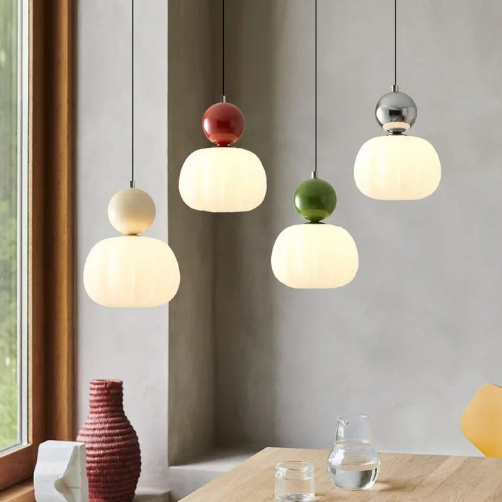 Set of colourful Nordic pendant lights in cream, red, green, and chrome, hanging above dining table