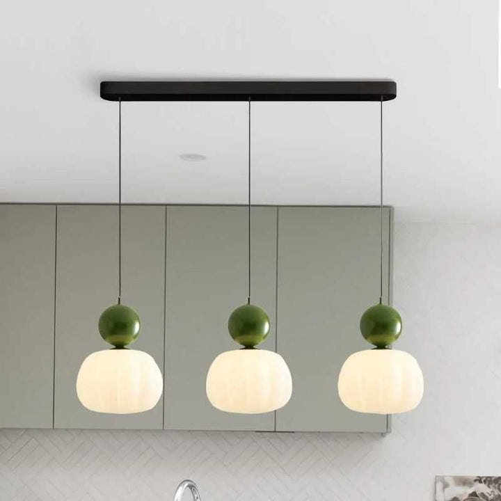 Set of three green-accent Art Deco pendant lights with round tops hanging in contemporary kitchen