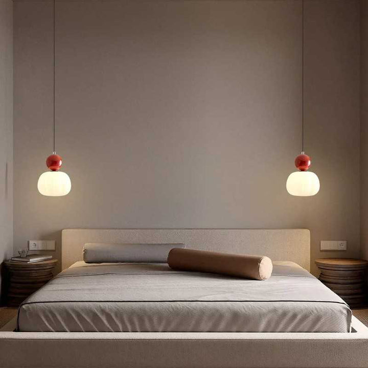 Pair of red-accent Art Deco pendant lights hanging symmetrically above modern bed