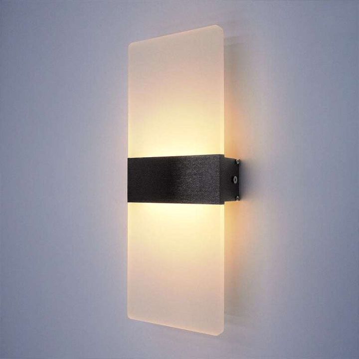 Modern LED wall lamp with frosted glass panel and brushed black center strip emitting warm light.