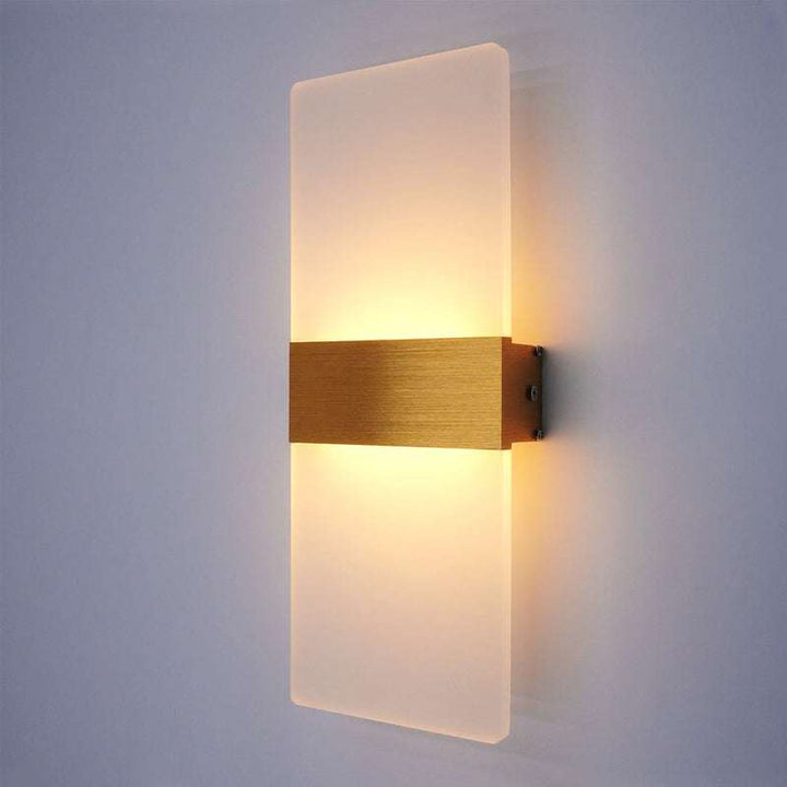 Modern LED wall lamp with frosted glass panel and brushed gold center strip glowing warmly.