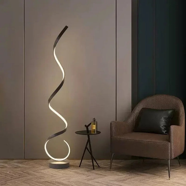Modern LED Spiral floor lamp in black aluminium beside sofa, soft warm glow for living room or bedroom