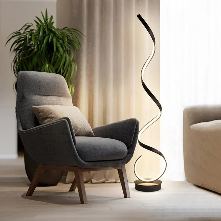 Modern LED Spiral floor lamp in black aluminium beside sofa, soft warm glow for UK living room or bedroom
