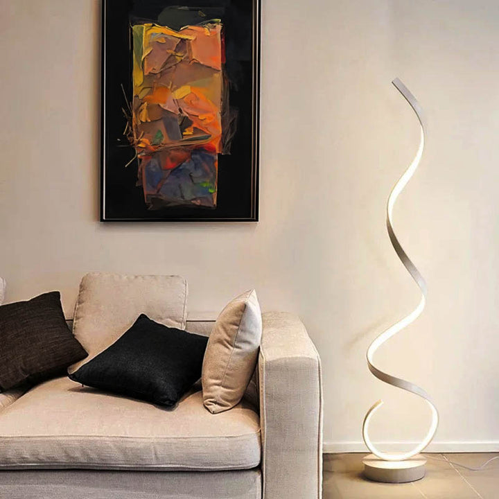 Modern White LED Spiral floor lamp in black aluminium beside sofa, soft warm glow for UK living room or bedroom