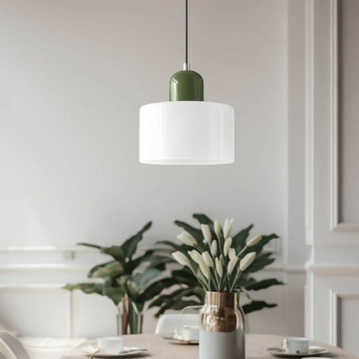 Nordic pendant light with deep green cap and white glass shade, hanging above a plant in a bright contemporary room.