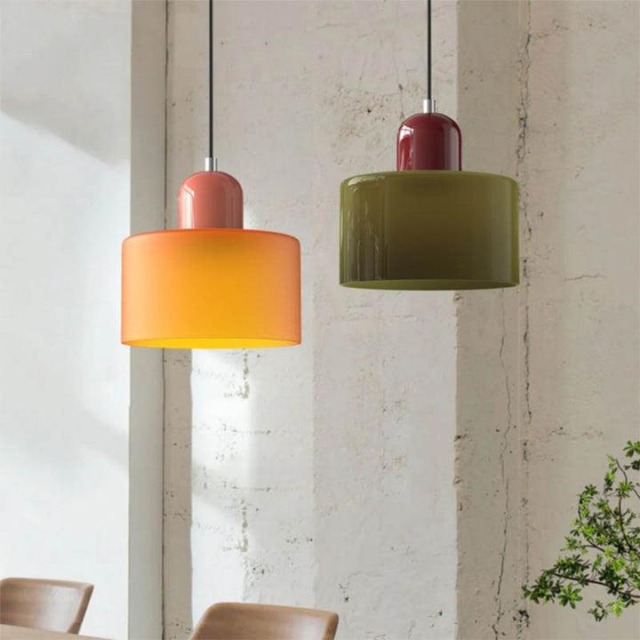 Warm-toned orange and green Nordic glass pendant lights hanging in a softly lit minimalist room with white walls.