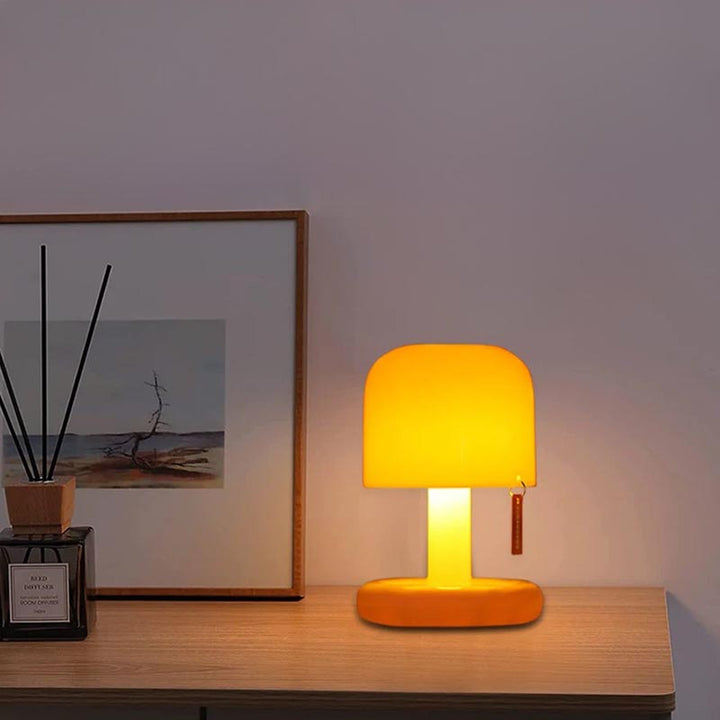 Soft LED mushroom lamp on bedside table with framed art, ideal for UK nightstand or bedroom lighting.