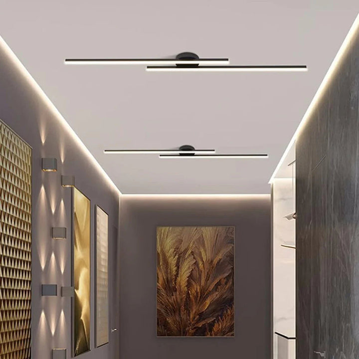 Modern black aluminium LED strip ceiling light illuminating a hallway with wall art.