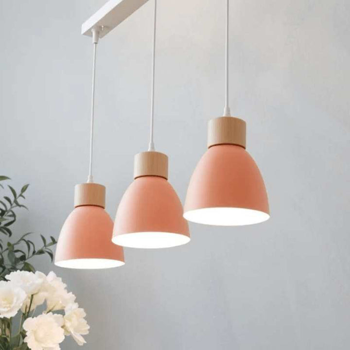 Triple coral pendant lights with wooden tops hanging from rectangular ceiling base