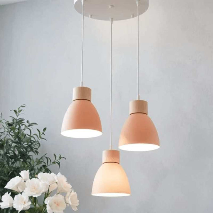 Triple pink pendant lights with round ceiling base and wooden detail