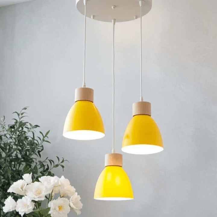 Cluster of three yellow pendant lights with wood detail on round ceiling base