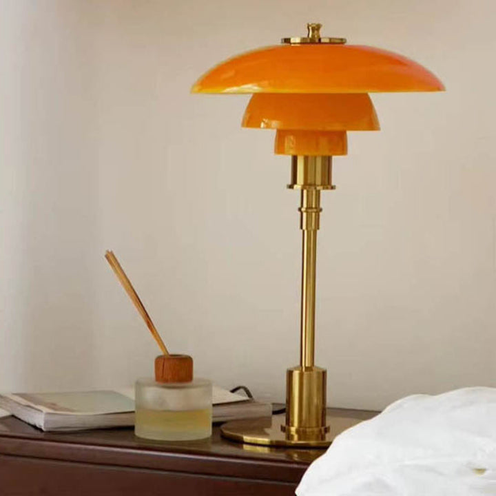 Nightstand Light with orange glass shade and brass base on a nightstand.