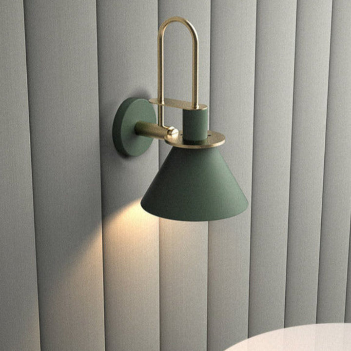 Green wall sconce with gold accents on a gray wall