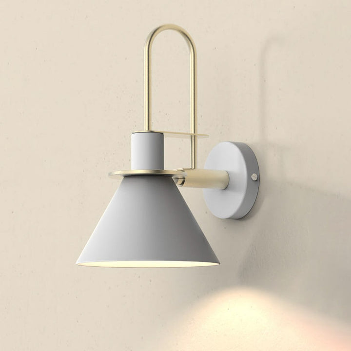 Wall-mounted lamp with gray shade and gold fixture on a beige wall