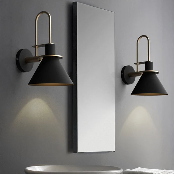 Two black wall sconces with gold accents on a gray wall.