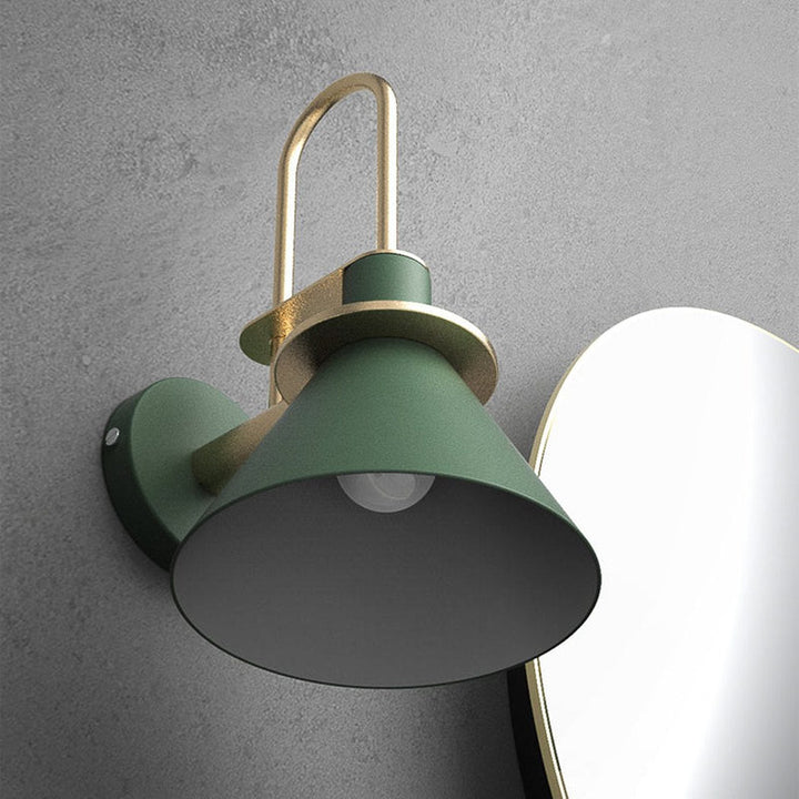 Green wall-mounted lamp with gold accents on a gray wall.