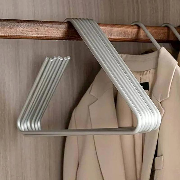 Set of silver triangle aluminium hangers on wooden rod, sleek and durable closet organisers for coats or shirts.