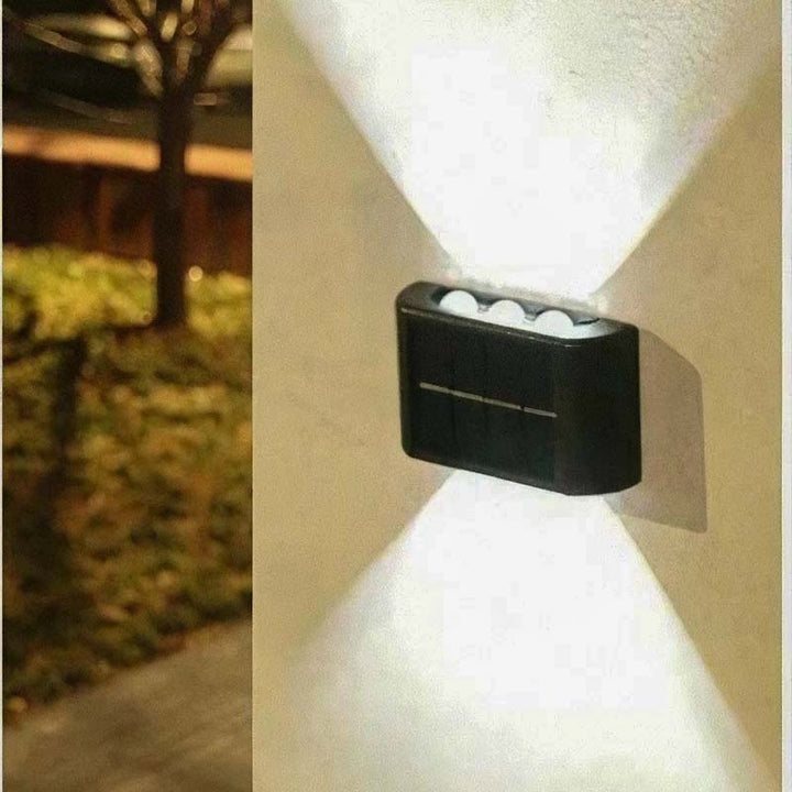 Set of three solar LED wall lamps mounted on stone garden wall, emitting soft light for UK outdoor pathways.