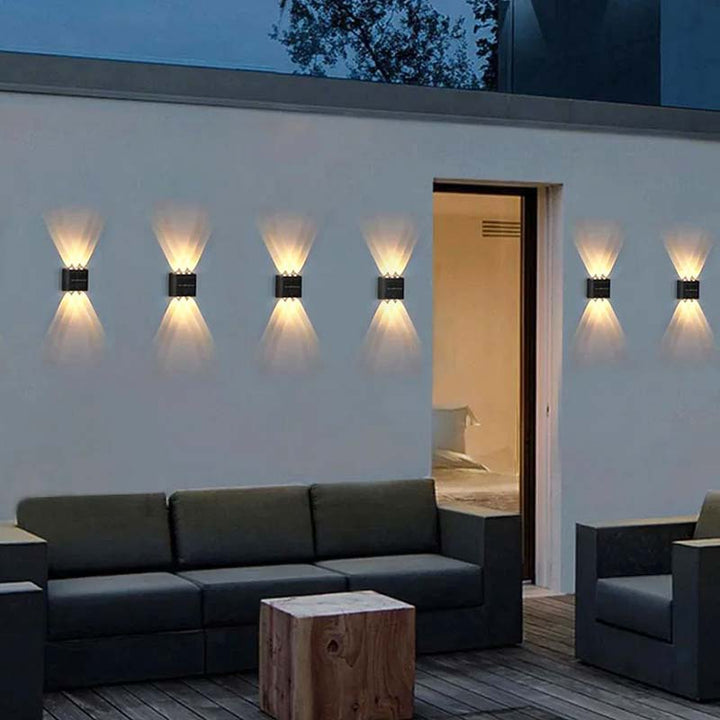 Multiple solar garden wall lights creating a warm glow around porch and patio area at night.