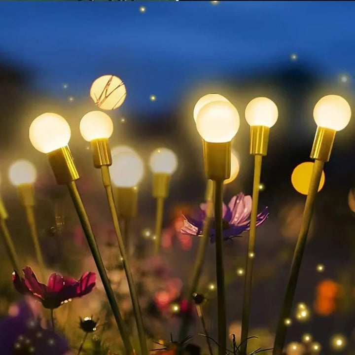 Decorative solar firefly lights with warm yellow LEDs blending into flower border for garden décor