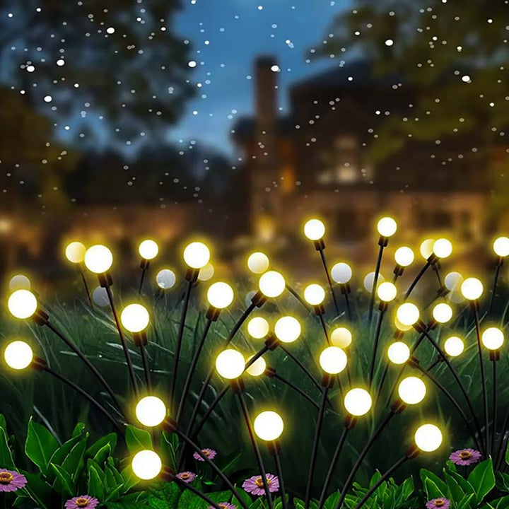 Solar-powered firefly effect LED lights creating magical glow across backyard lawn setting
