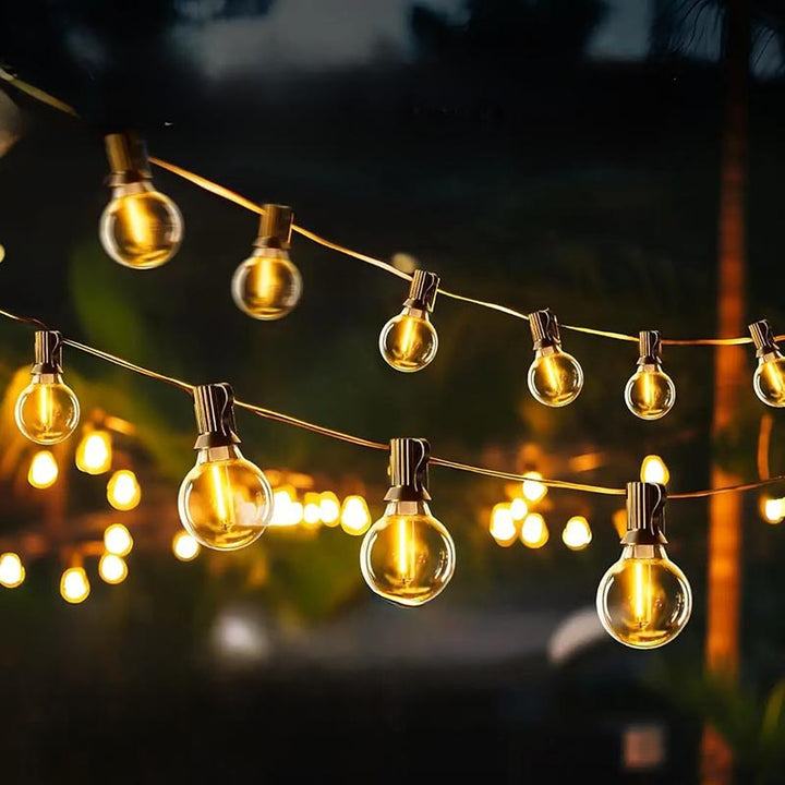 Golden glow fairy lights wrapped along tree and fence for decorative garden lighting setup at dusk.
