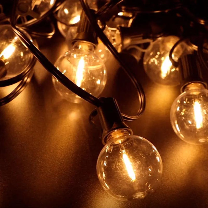 Warm white solar garden string lights with shatterproof LED bulbs on black cable, ideal for patio and outdoor parties.