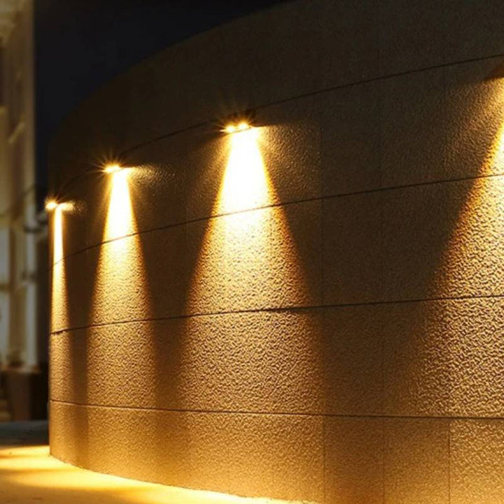 Row of LED solar outdoor wall lights illuminating a curved exterior wall at night