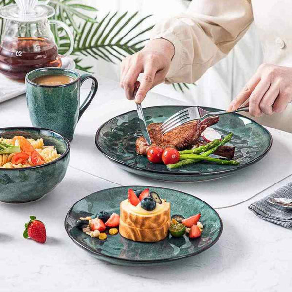 Person eating a meal with  teal ceramic dinnerware on a white table.