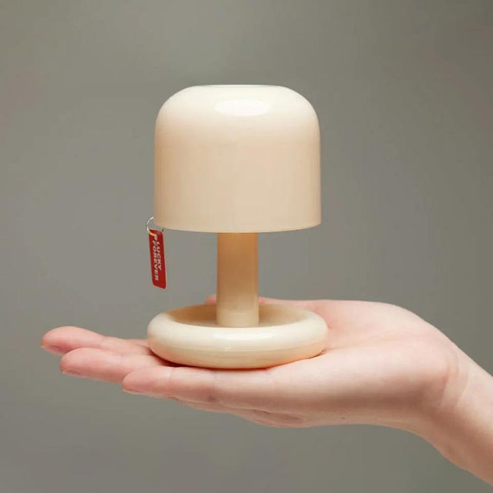 Touch control mushroom table lamp held in one hand, showcasing compact and portable size for travel or home.