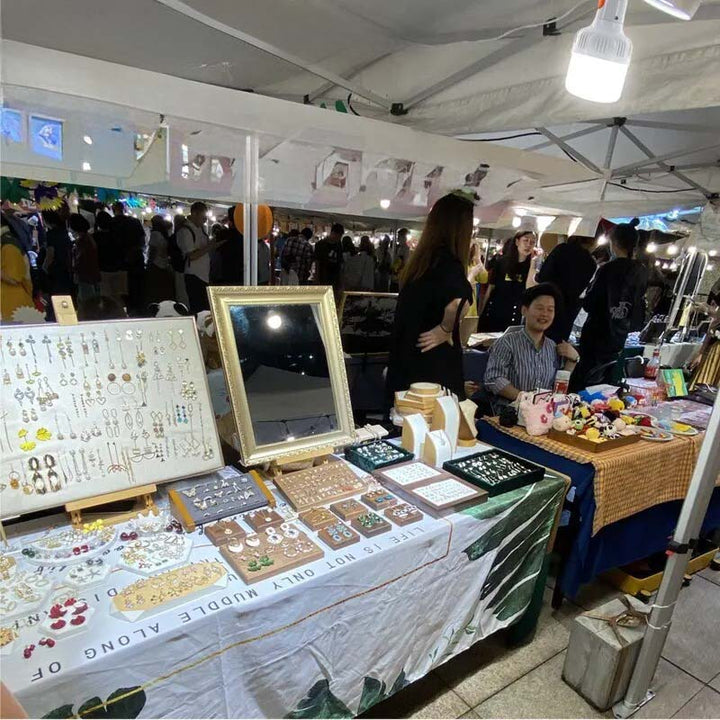 USB rechargeable LED camping lamp illuminating an outdoor market stall, portable hook light for events