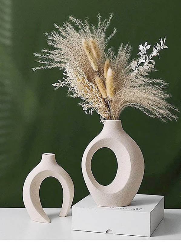 Beige ceramic vase pair with pampas grass, styled on white plinth for calm, elegant Scandinavian home decor.