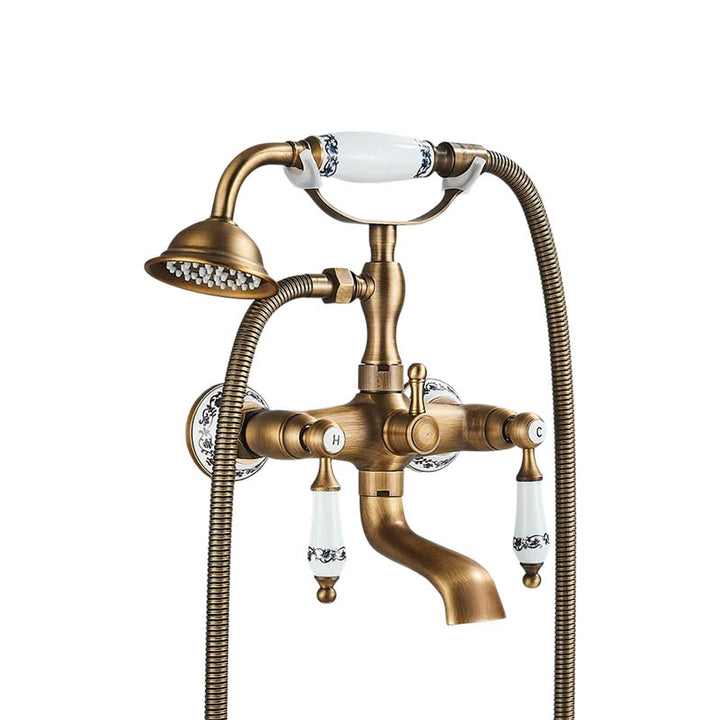 Elegant vintage wall-mounted brass bath faucet with handheld sprayer and white ceramic handles.