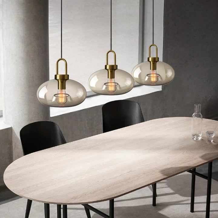Horizontal set of 3 glass pendant lights styled above oval dining table—elegant lighting for open-plan UK dining rooms.