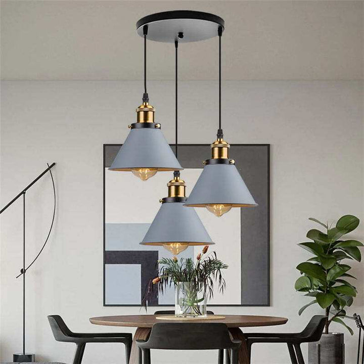 Grey retro industrial pendant lights in a trio design above round dining table, modern interior.