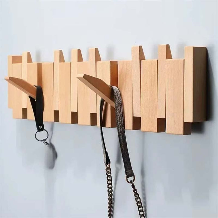 Wooden wall-mounted coat rack with multiple hooks holding a belt and a dog leash on a light gray background.