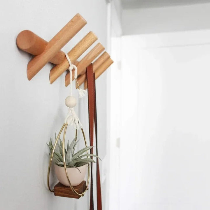 Minimalist oak coat rack mounted on wall, ideal for hanging plants, bags, and accessories in modern homes