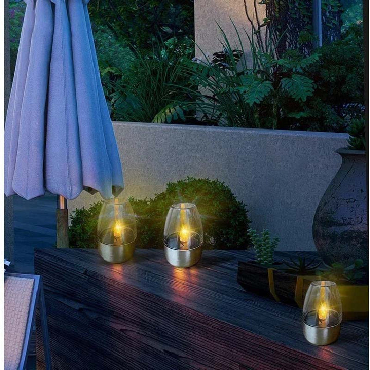 Solar-powered LED candles placed on a patio deck, creating atmospheric lighting for UK outdoor evening gatherings.