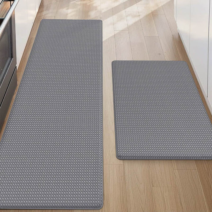 Two grey textured kitchen mats on a wooden floor.