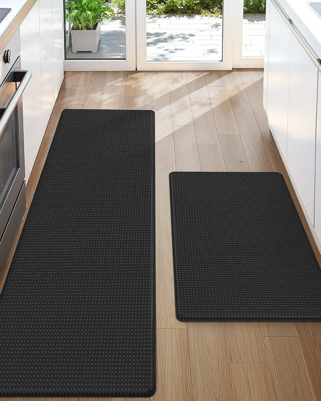 Two black kitchen mats on a wooden floor in a modern kitchen.