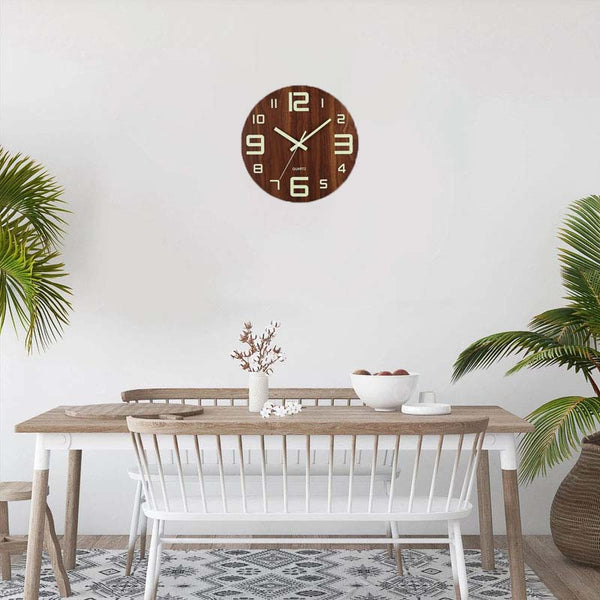 Wooden wall clock on a white wall above a dining table with chairs.
