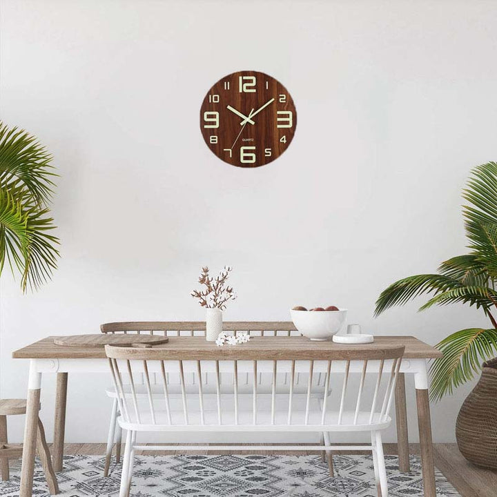 Wooden wall clock on a white wall above a dining table with chairs.
