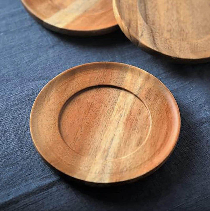 Three wooden coasters on a blue fabric surface