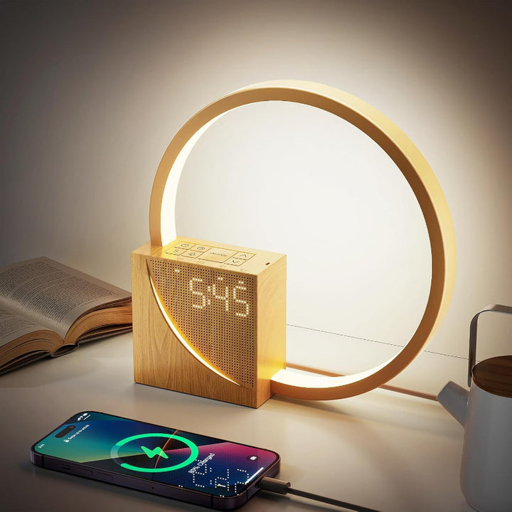 Wooden clock with circular light feature on a table next to an open book and smartphone.