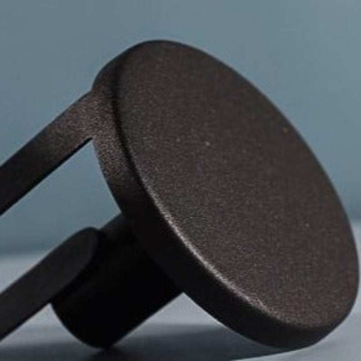 Close-up of round base of matte black candle holder with fine textured iron finish