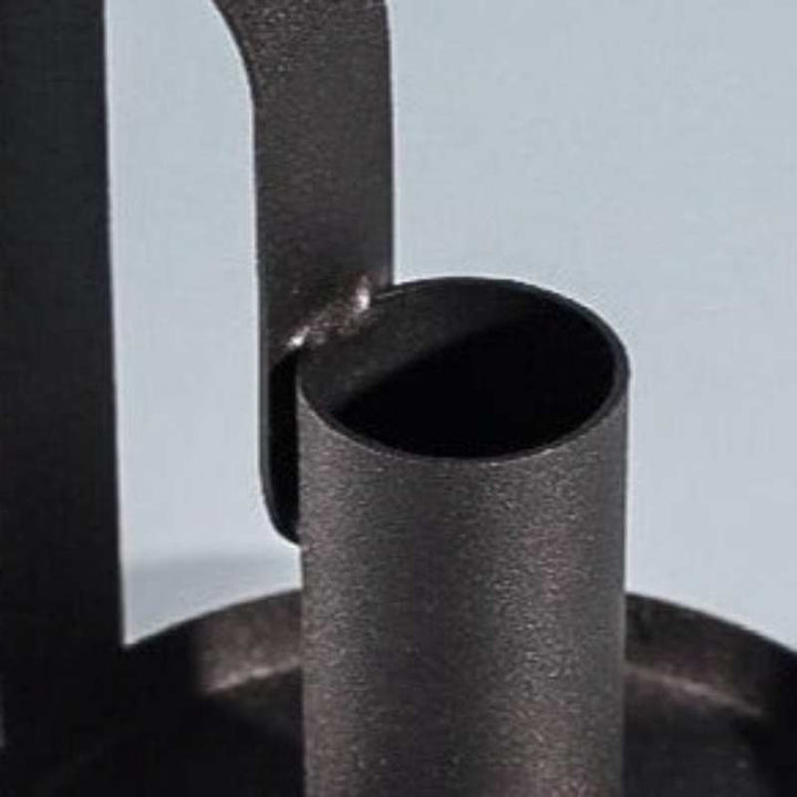 Detail of cylindrical holder and curved handle joint on matte black iron candle holder